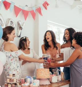 Two women, one pregnant, holding a teddy bear and smiling