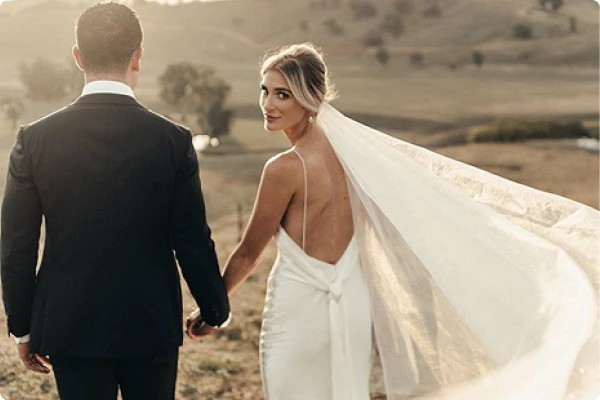 Bride and groom walking together outdoors in a sunny field